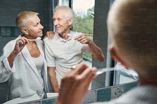 Charming aged woman expressing positivity while cleaning teeth after breakfast