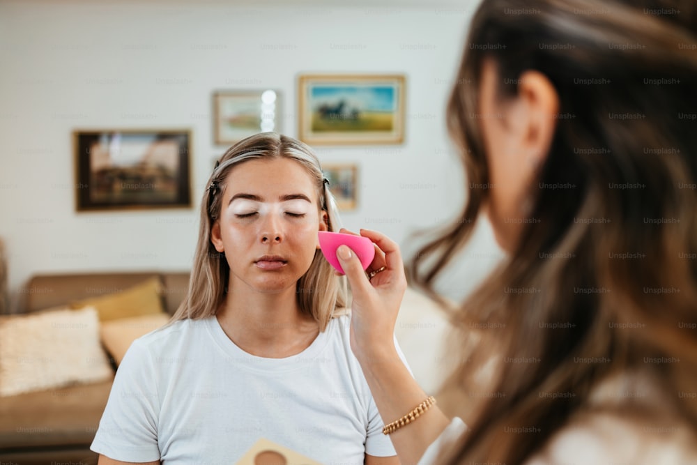 Makeup process. Professional artist applying make up on model face. Close up portrait of beautiful blonde woman in beauty saloon.