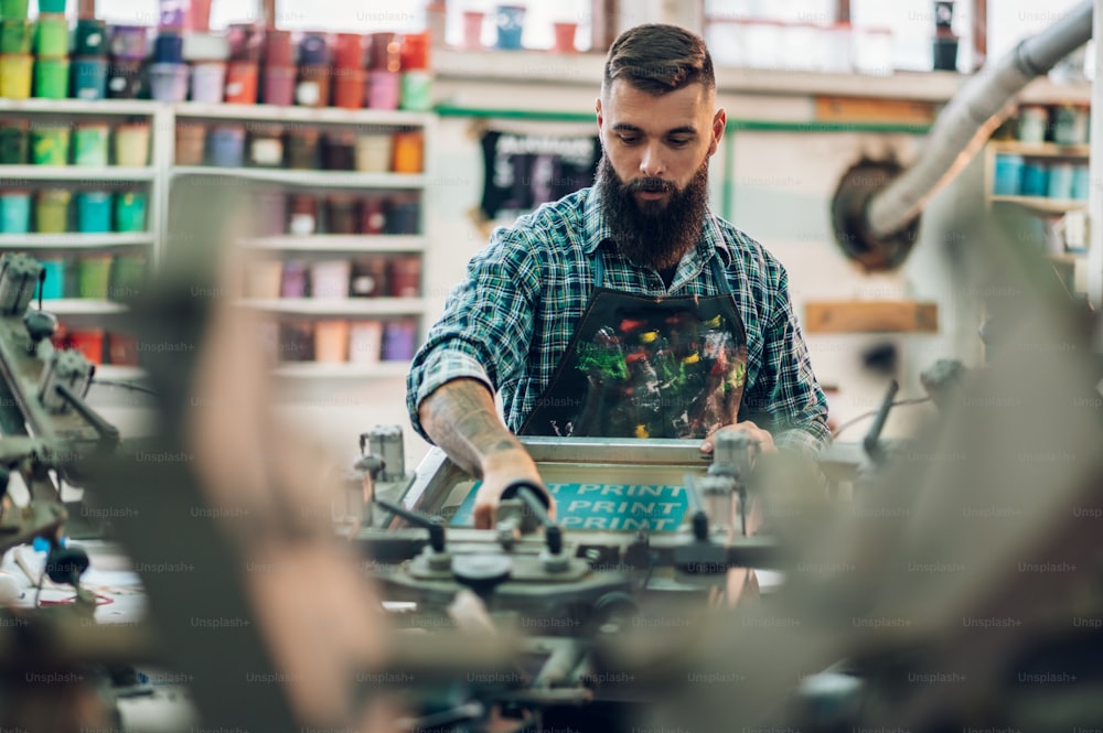 Male worker using printing machine in a workshop