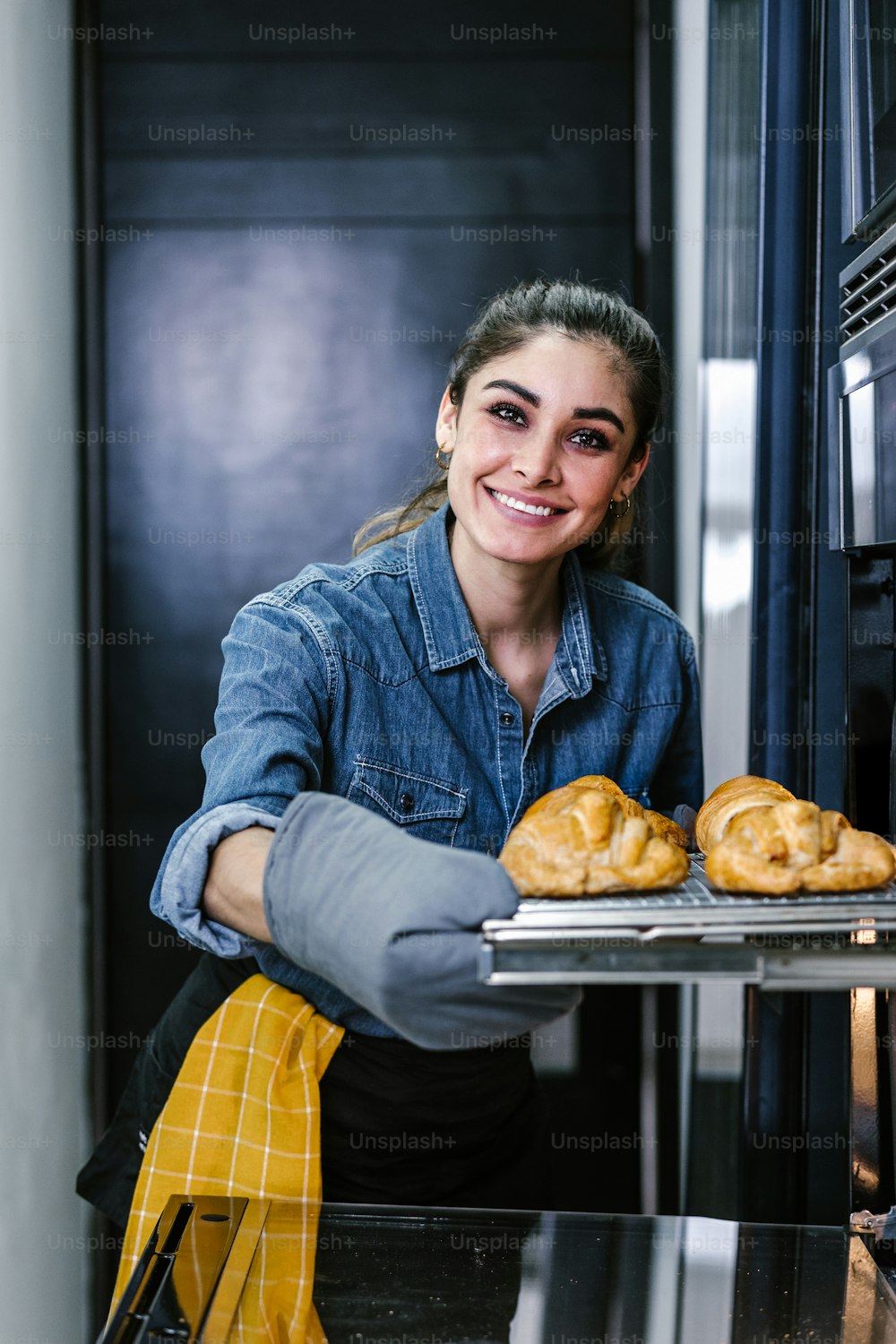 young Latin woman baking croissant on oven in kitchen in Mexico Latin America