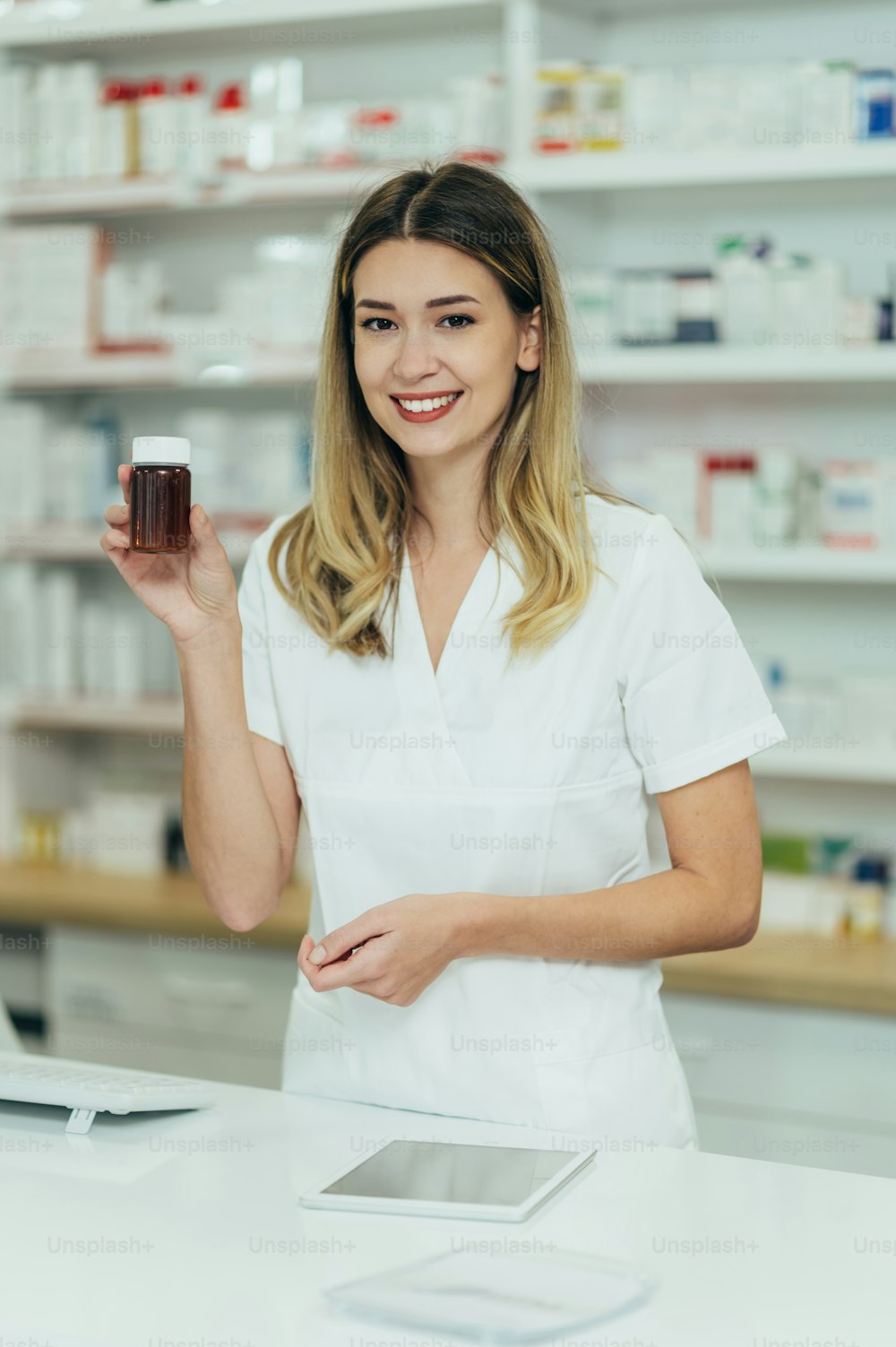 Ritratto di una bella farmacista che lavora in una farmacia e tiene una bottiglia di farmaci