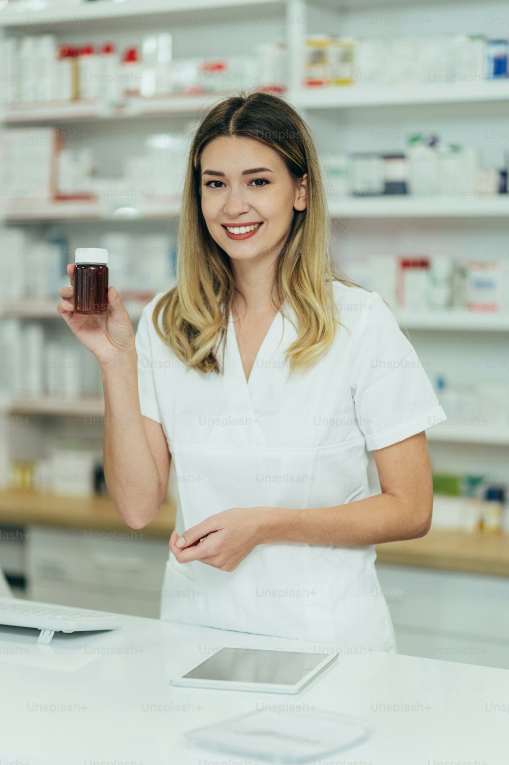 Retrato de una hermosa farmacéutica que trabaja en una farmacia y sostiene un frasco de medicamentos