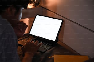 Young man laying on bed and working with computer tablet at late night.