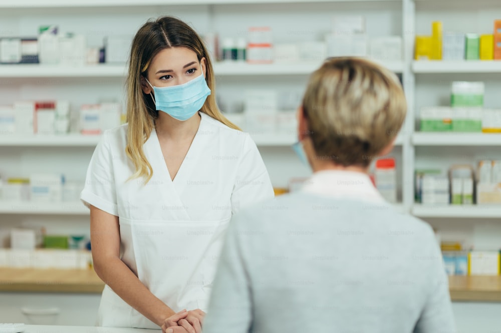 Farmacista che indossa una maschera protettiva e serve un paziente cliente in una farmacia