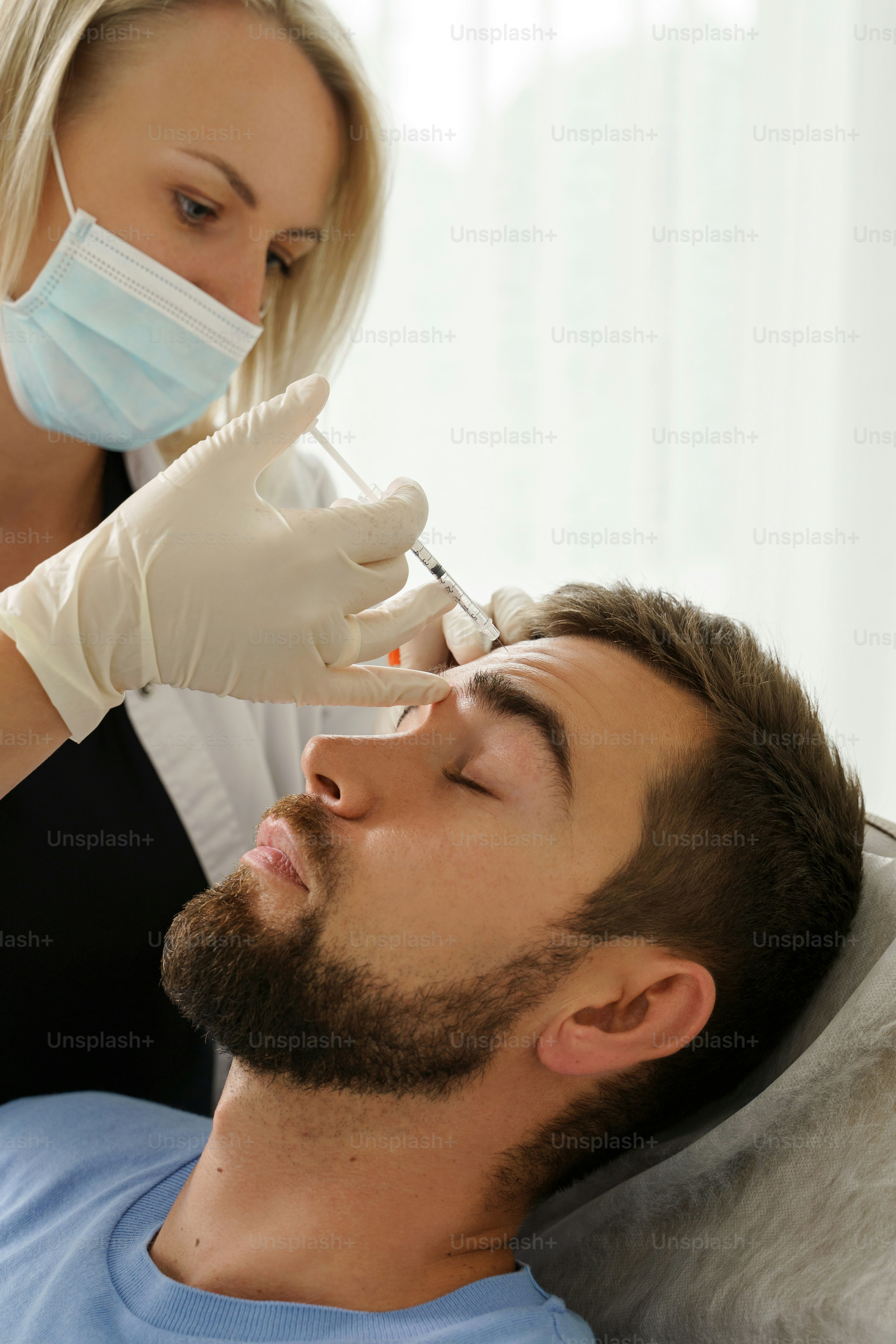 Female doctor and male client during filler injections in aesthetic medical clinic