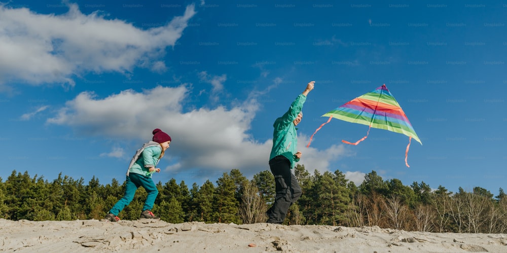 Padre con la figlia di 5 anni che fa volare un aquilone sulla spiaggia di sabbia. Allegre attività in famiglia all'aperto. Banner panoramico orizzontale.