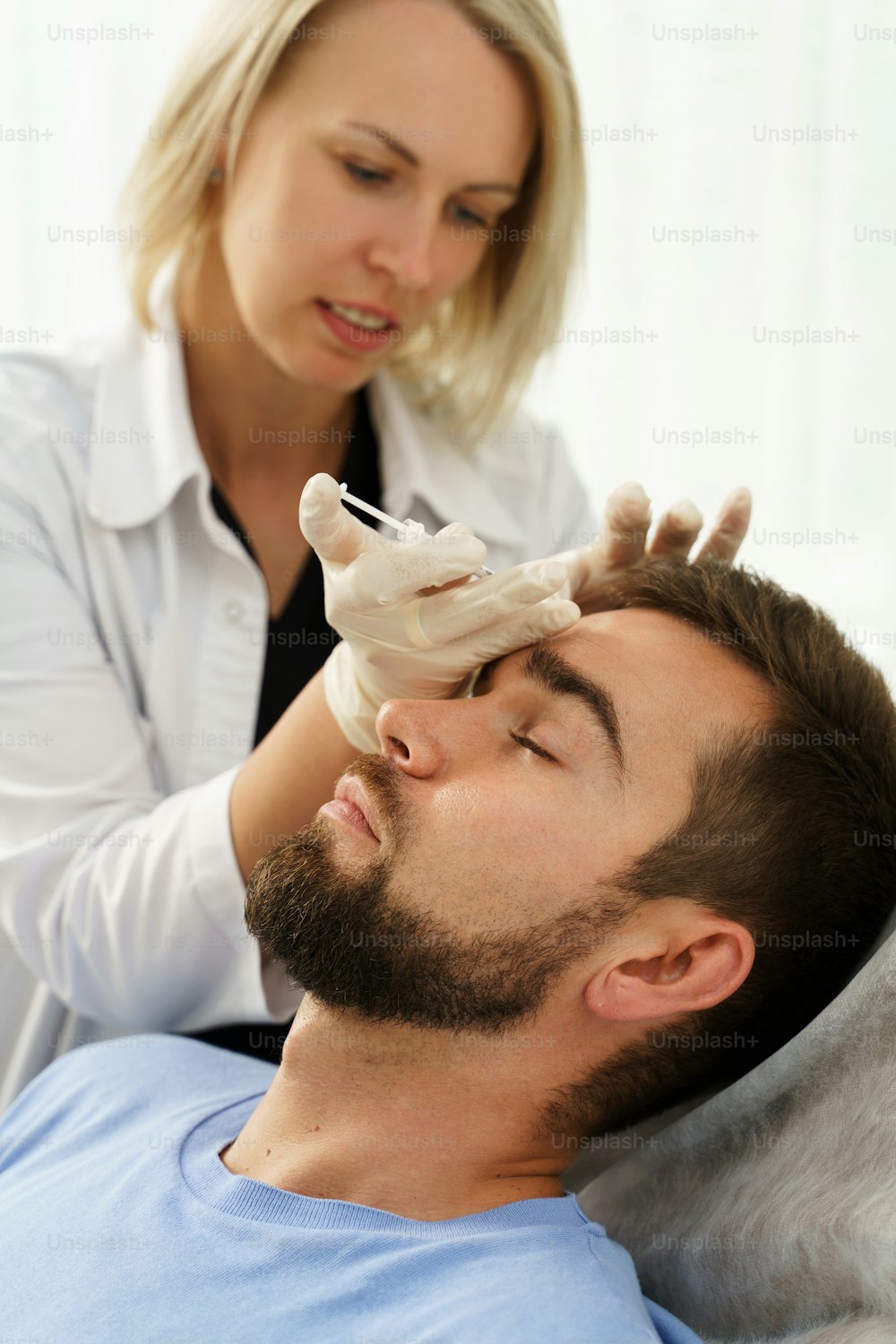 Female doctor and male client during filler injections in aesthetic medical clinic