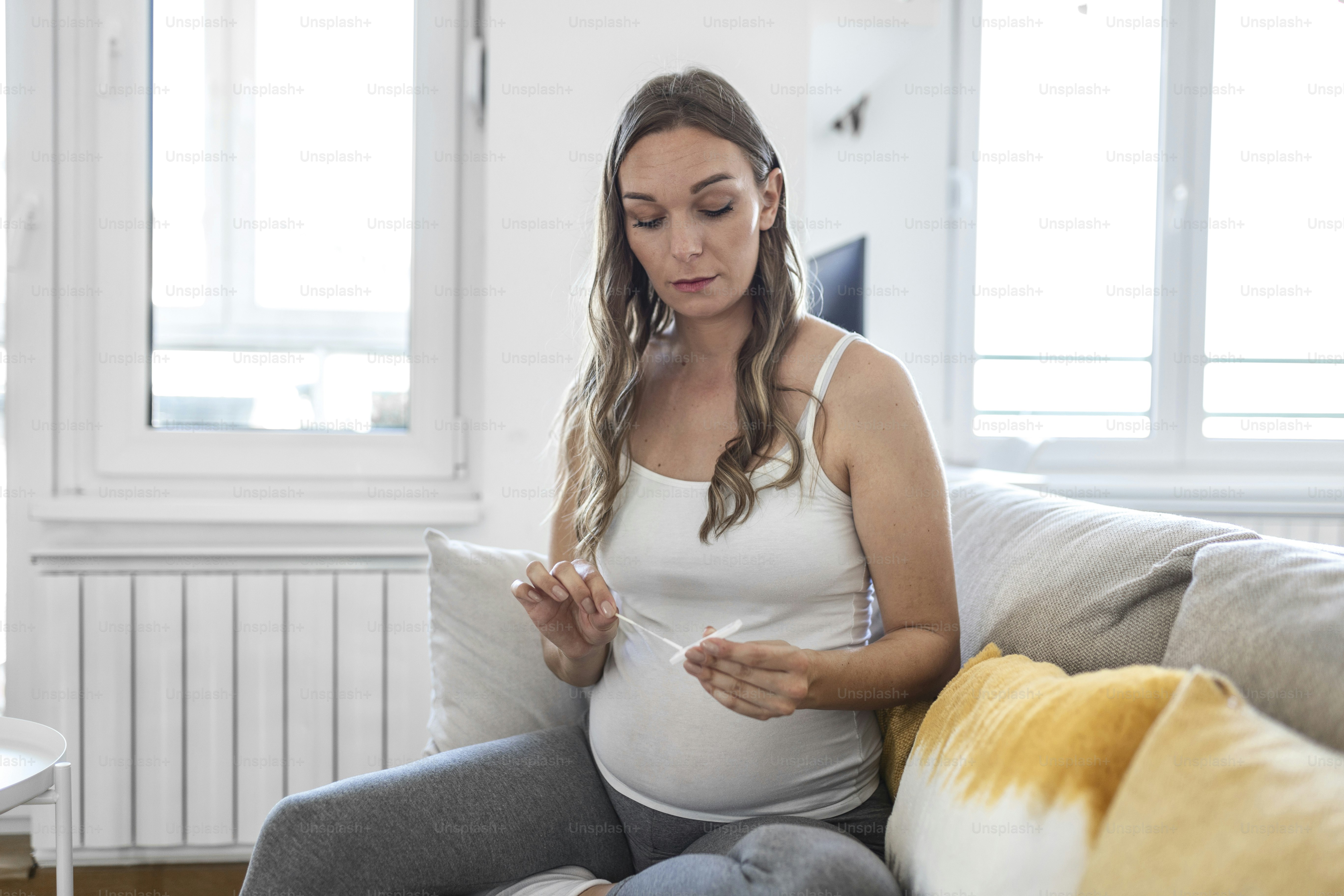 Pregnant woman taking a Self-swabbing home tests for COVID-19 at home with Antigen kit. Introducing nasal stick to check the infection of Coronavirus. Quarantine, pandemic.