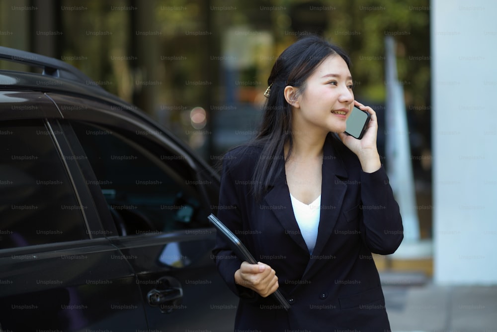 ビジネスクライアントと電話で話している路上で成功したビジネスウーマン。アーバンビジネスライフのコンセプト。