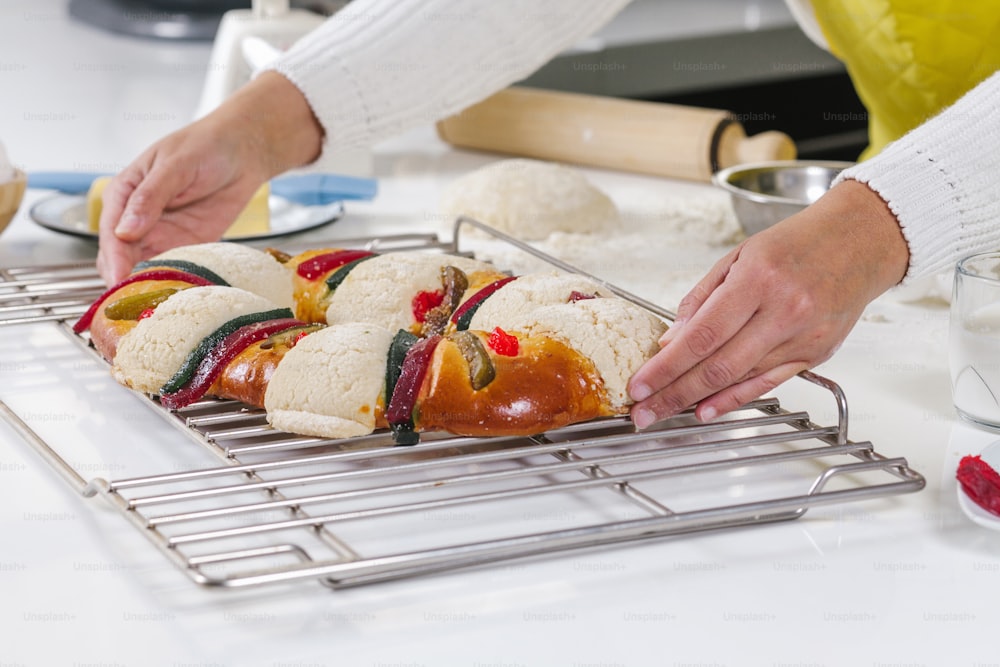 mexican woman baking a traditional rosca de reyes or epiphany cake on the oven in kitchen at home for Kings Day in Mexico Latin America