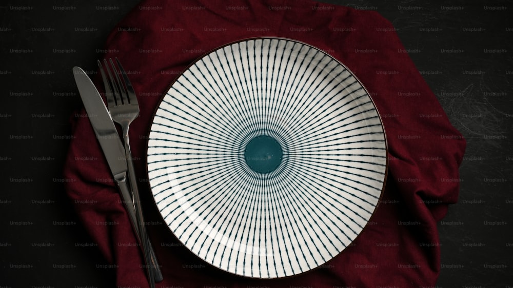 Leerer Keramikteller mit Besteck und Serviette auf dem Esstisch. Lebensmittelbehälter. Tischdekoration. Draufsicht, flache Verlegung