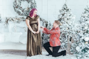 Homosexual gay butch woman proposing her girlfriend to marry her and giving her box with ring. LGBTQ lesbian couple celebrating Christmas or New Year winter holiday. Real authentic positive emotion