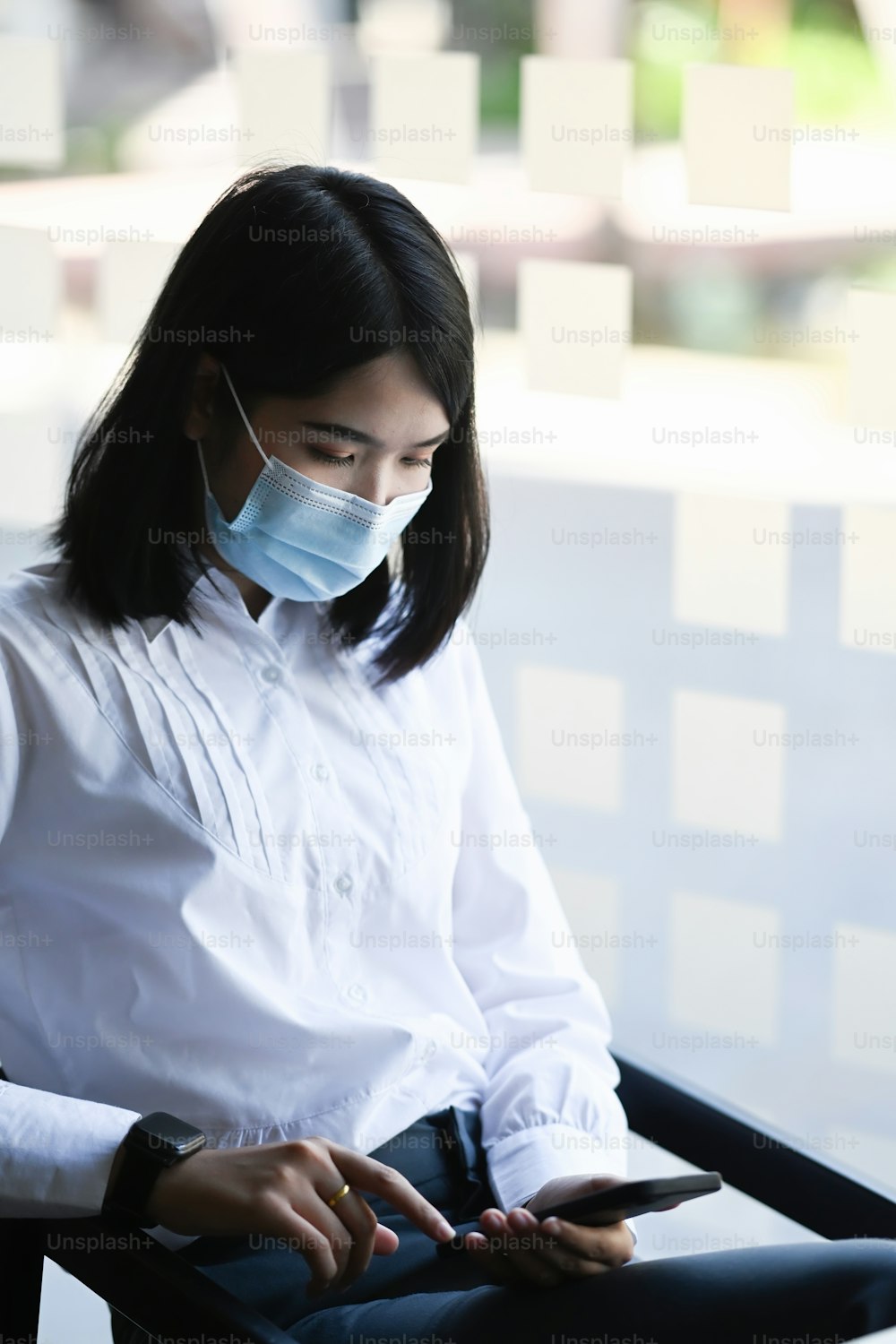 Young businesswoman wearing face mask while using smart phone in office.