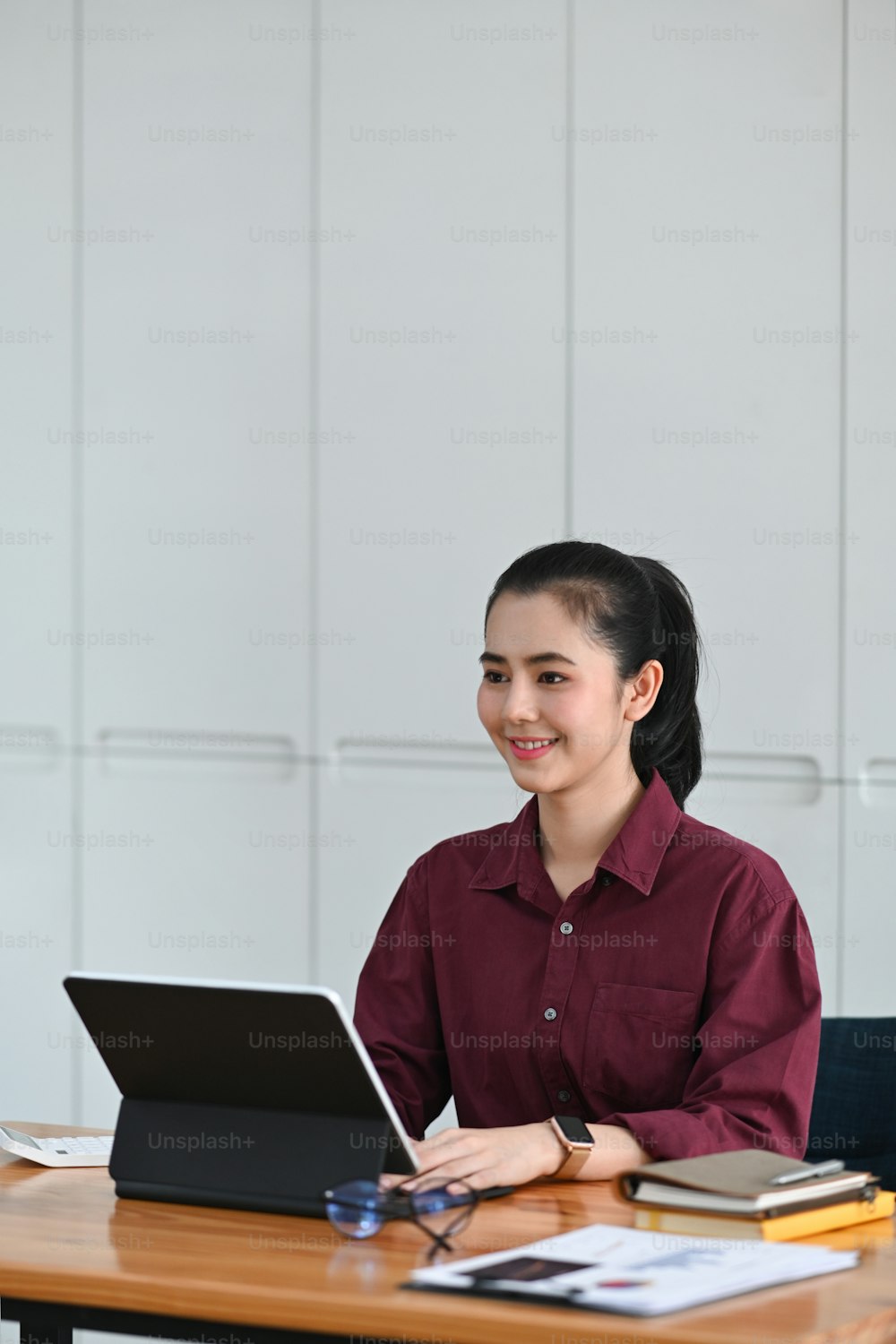 Mujer de negocios sonriente sentada en el escritorio de su oficina y trabajando con una tableta de computadora.