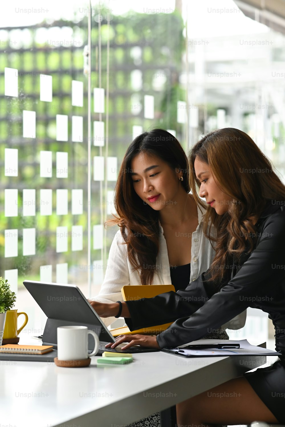 사무실에서 컴퓨터 태블릿으로 함께 일하는 두 명의 여성 비즈니스 동료.