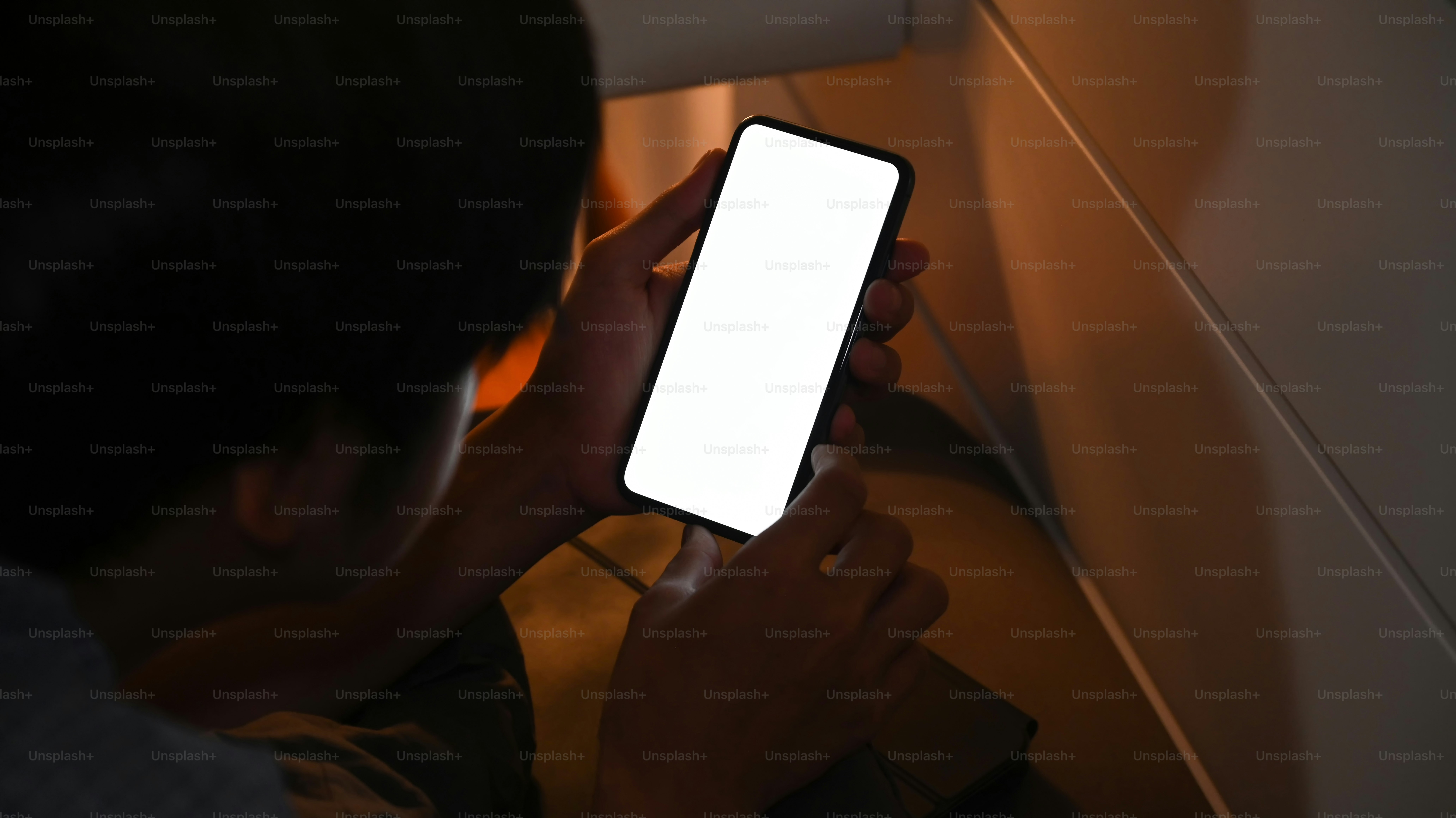 Young man using smart phone at night while lying on his bed.