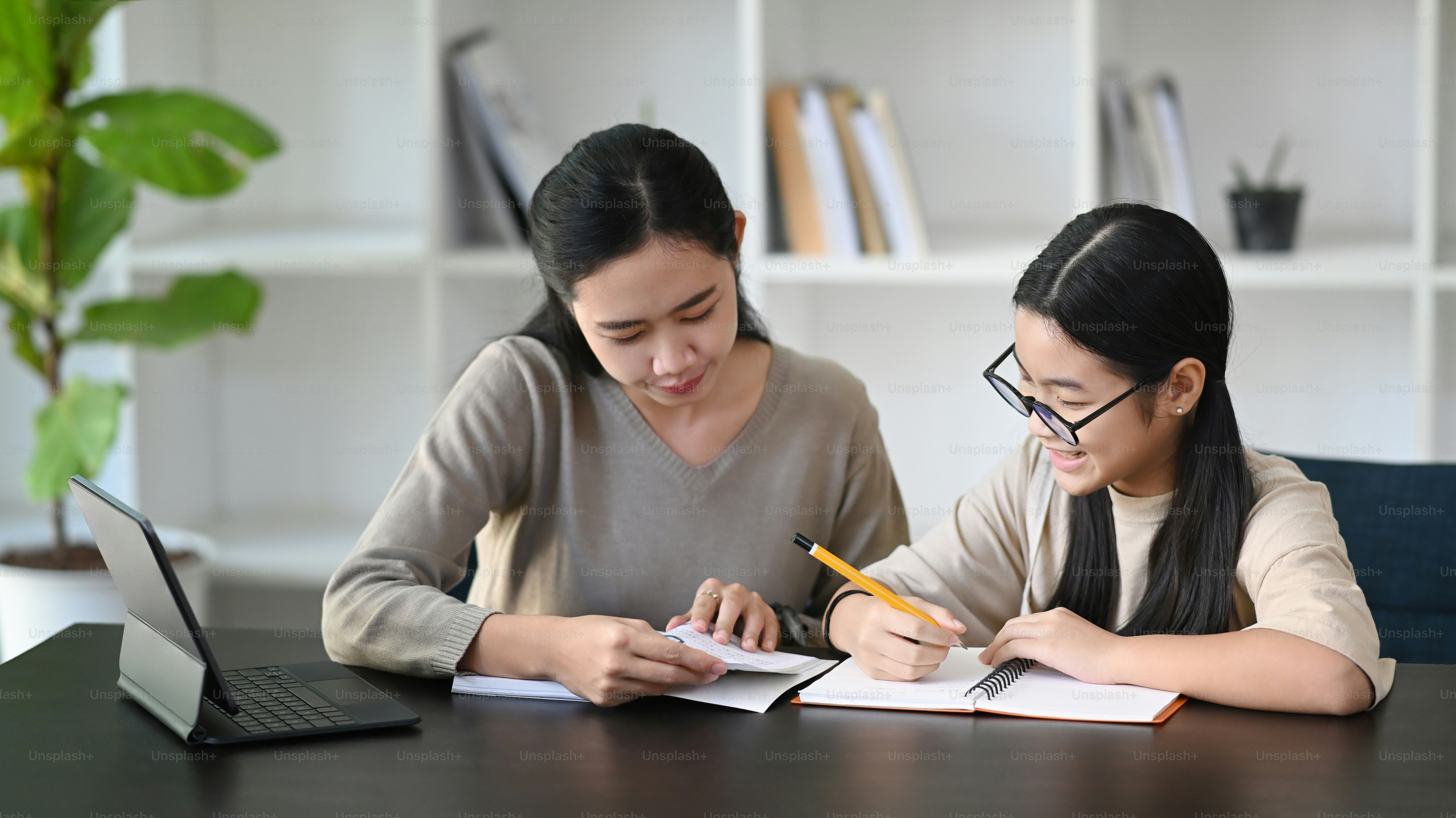 Foto Madre asiática atenta ayudando a su hija a hacer la tarea en casa ...