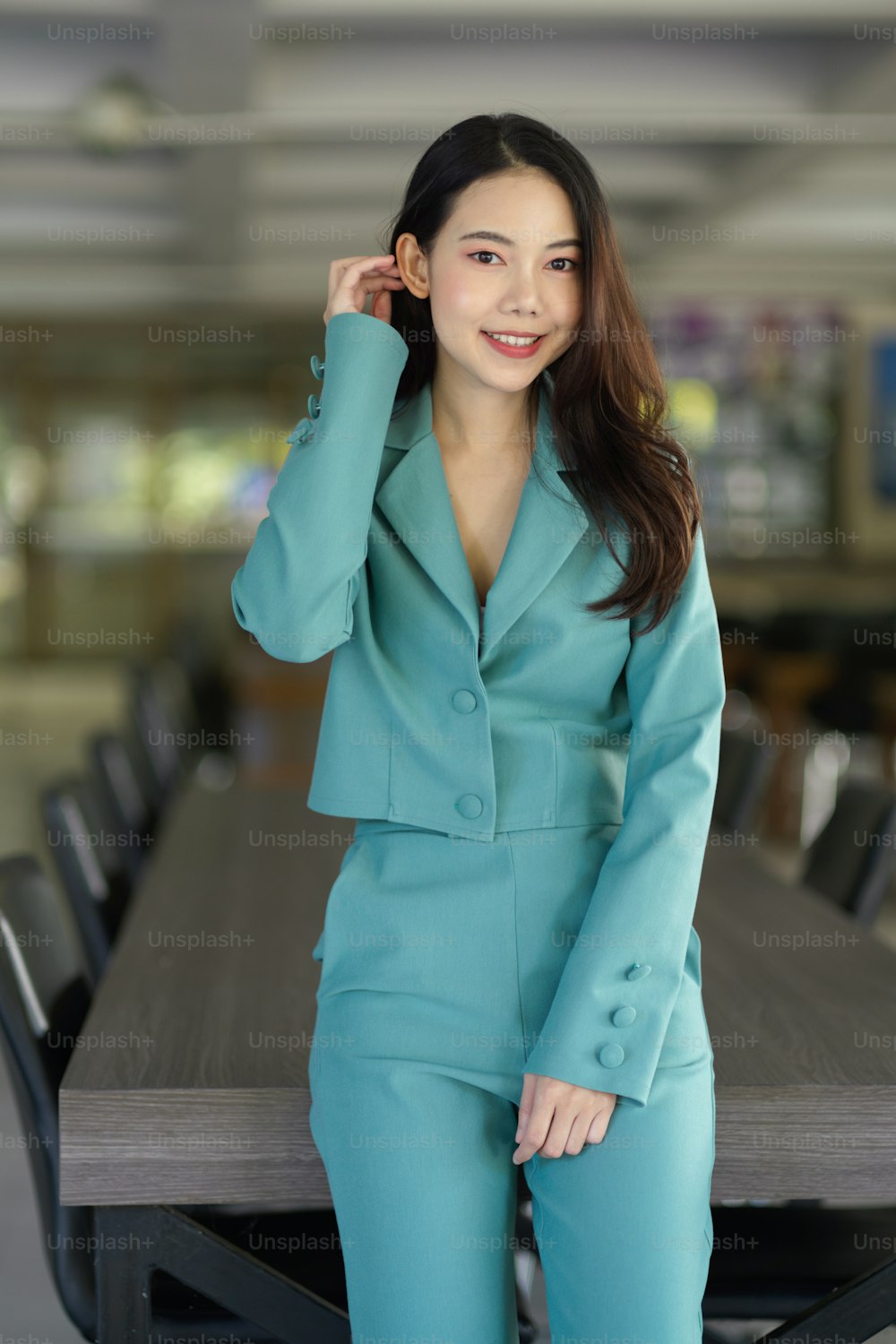 Ritratto di bella giovane donna d'affari asiatica in abito elegante in piedi nella sala del consiglio.