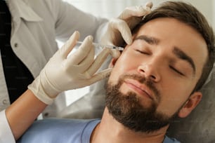 Female doctor and male client during filler injections in aesthetic medical clinic