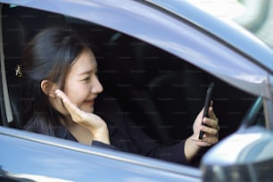Giovane donna attraente che parla al telefono, in una videochiamata mentre è in macchina. Tecnologia wireless, connessione internet online. lavoro a distanza.