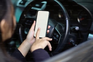 Close-up of a woman or businesswoman using modern smartphone in her car. mobile phone blank screen mockup.