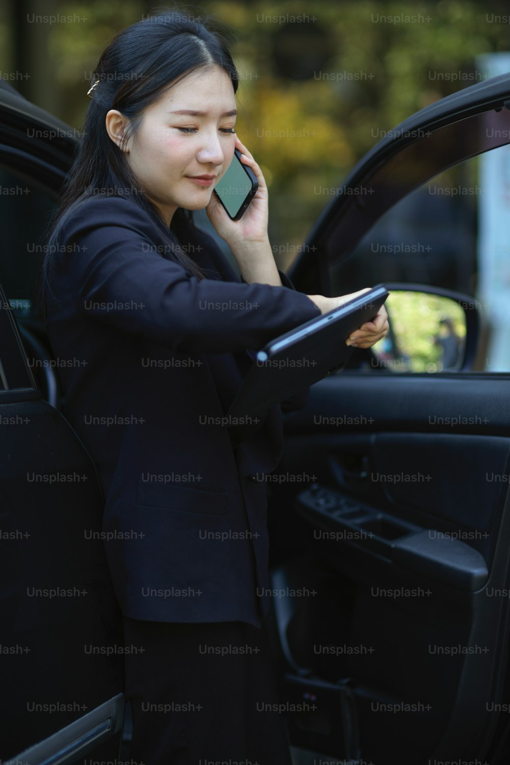 プロのビジネスウーマンの肖像画は、車の近くで腕時計を見ながら電話で話します。忙しいビジネスウーマンのコンセプト。