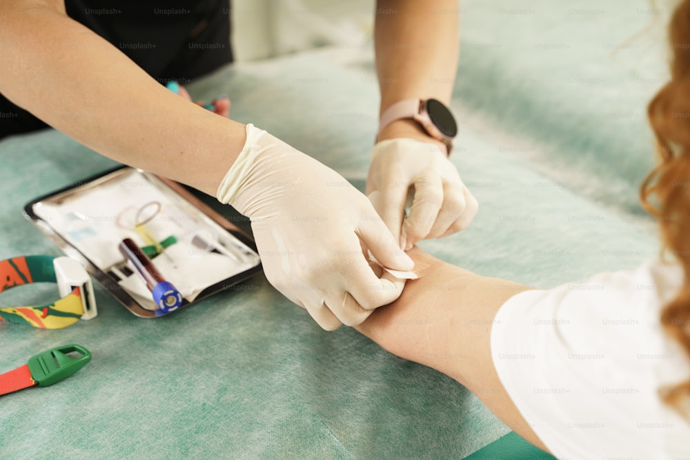Nurse collecting patient's blood sample for test or donation in medical clinic