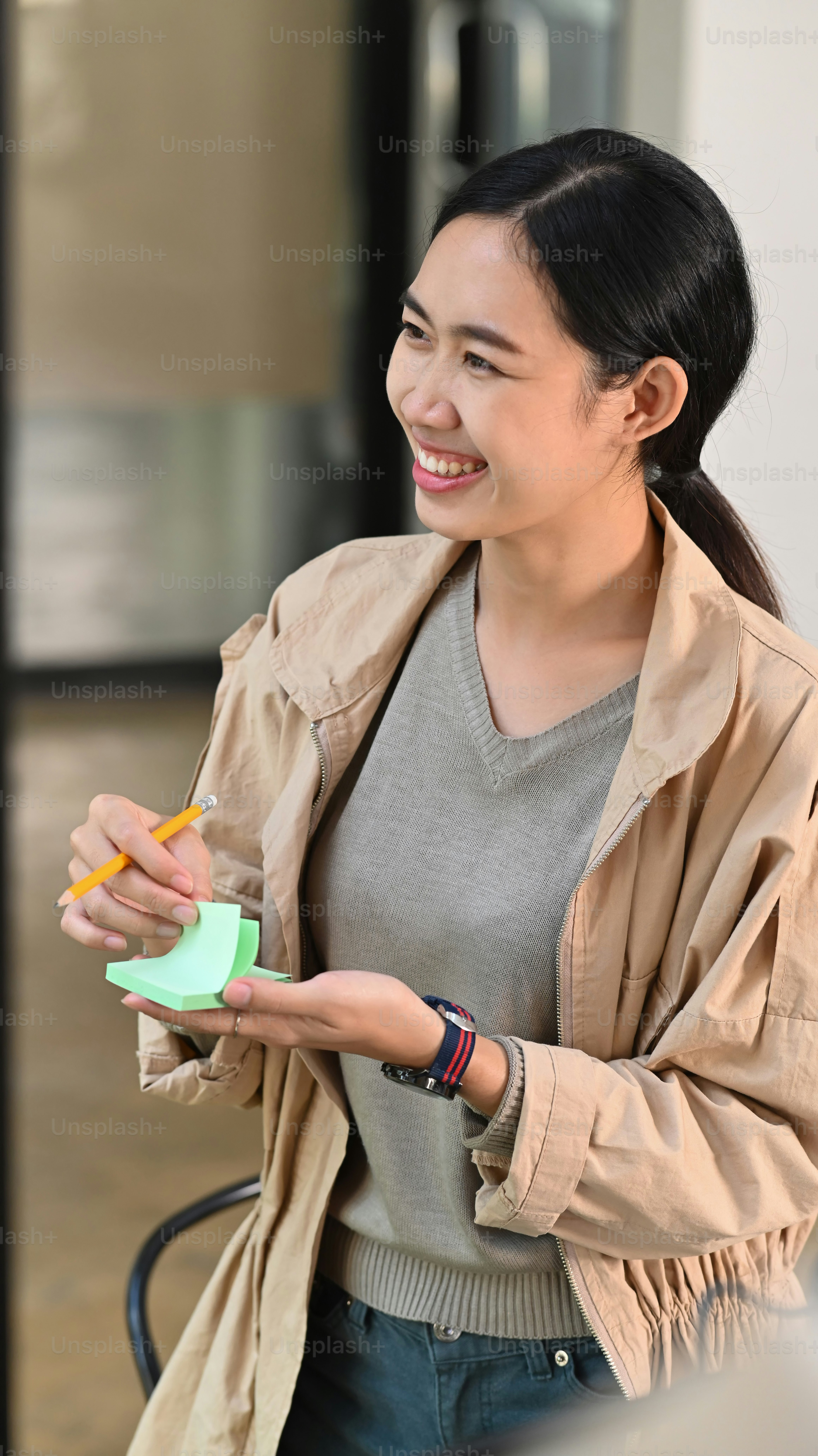 Cheerful female designer writing new ideas on sticky notes. photo ...
