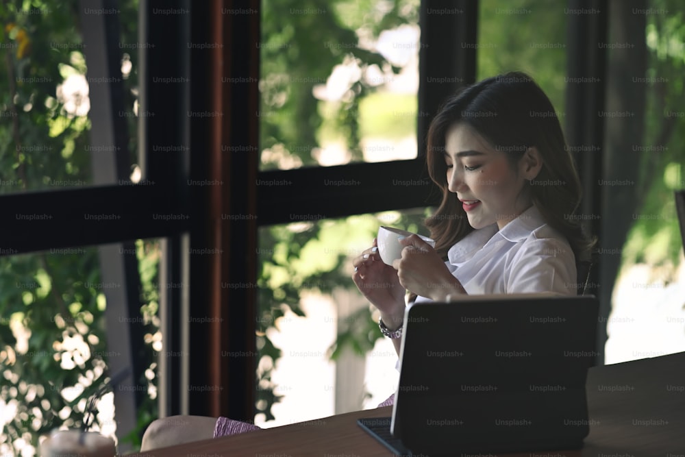 Thoughtful businesswoman sitting in office and drinking hot coffee.