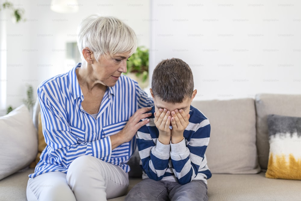 Amorevole comprensione vecchia nonna che abbraccia il piccolo ragazzo che piange confortando il nipote sconvolto, la nonna premurosa anziana che abbraccia il bambino che consola il bambino in lacrime, il supporto dell'empatia della nonna per il nipote