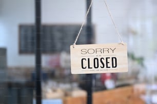 Closed sign board hanging on the glass of store window.