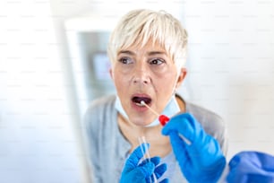 Physician wearing personal protective equipment performing a Coronavirus COVID-19 PCR test, patient nasal NP and oral OP swab sample specimen collection process, viral rt-PCR DNA diagnostic procedure