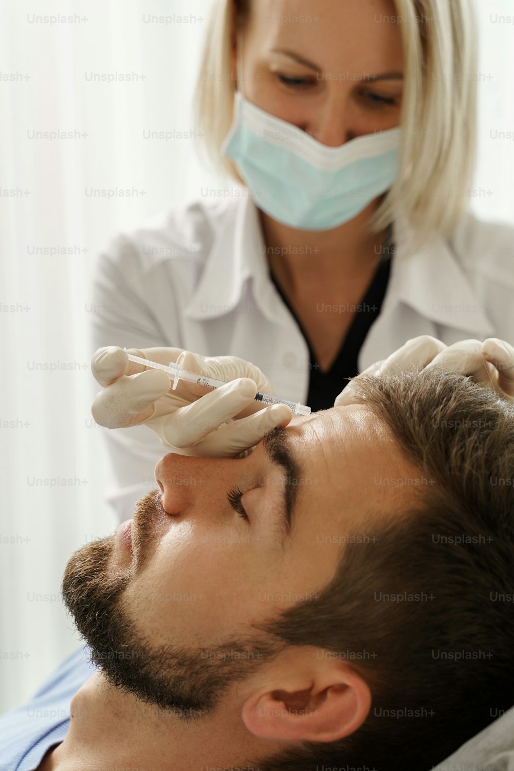Female doctor and male client during filler injections in aesthetic medical clinic