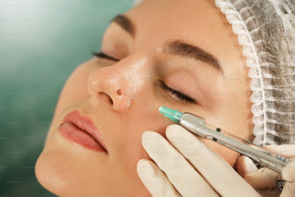 Woman client getting injection of local anesthetic before mole removal treatment in a medical aesthetic clinic