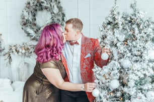 Couple de lesbiennes LGBTQ célébrant ensemble les vacances d’hiver de Noël ou du Nouvel An. Dame femme gay avec partenaire butch décorant l’arbre de Noël à la maison. Esprit d’humeur des vacances d’hiver.