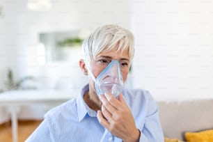 病気の高齢女性が吸入をすると、薬は最高の薬です。酸素マスクを着用し、covid-19の治療を受けている病気の高齢女性。吸入器を持った年配の女性