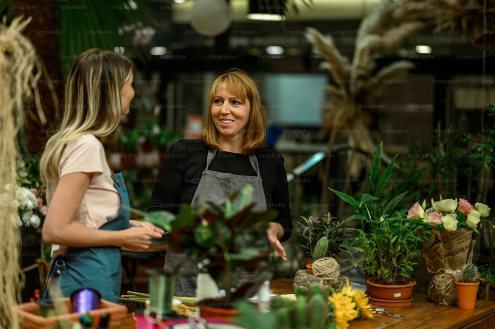 Experienced woman florist helping young employee how their business works and how to deal with customers