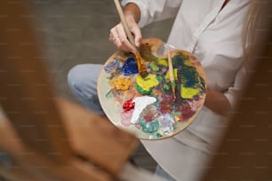 마스터 클래스에서 그림을 그리는 동안 이젤 맞은편에 앉아 있는 편안한 여성