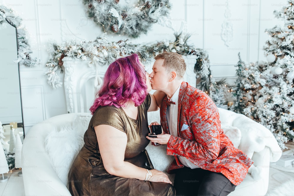 Homosexual gay butch proponiendo a su novia casarse con ella y dándole caja con anillo. Pareja de lesbianas LGBTQ celebrando las vacaciones de invierno de Navidad o Año Nuevo. Emoción positiva real y auténtica