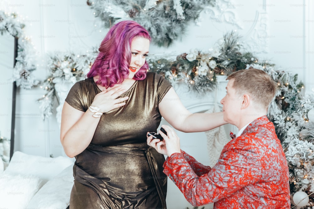 Homosexual gay butch woman proposing her girlfriend to marry her and giving her box with ring. LGBTQ lesbian couple celebrating Christmas or New Year winter holiday. Real authentic positive emotion
