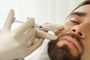 Cliente masculino durante inyecciones de relleno en clínica médica estética