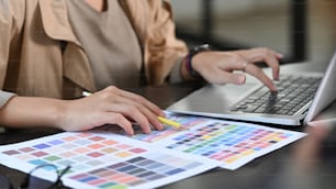 Cropped shot graphic designer working with color swatches in creative office.