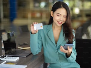 Mulher de negócios atraente, funcionária com smartphone e cartão de crédito nas mãos. pagamento online, conceito de compras online.