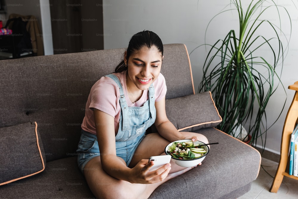 young latin woman eating vegetable or salad bowl, healthy food at home in Mexico Latin America