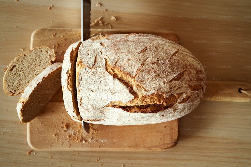 Cortar una hogaza de pan de masa madre casera con un cuchillo, vista superior