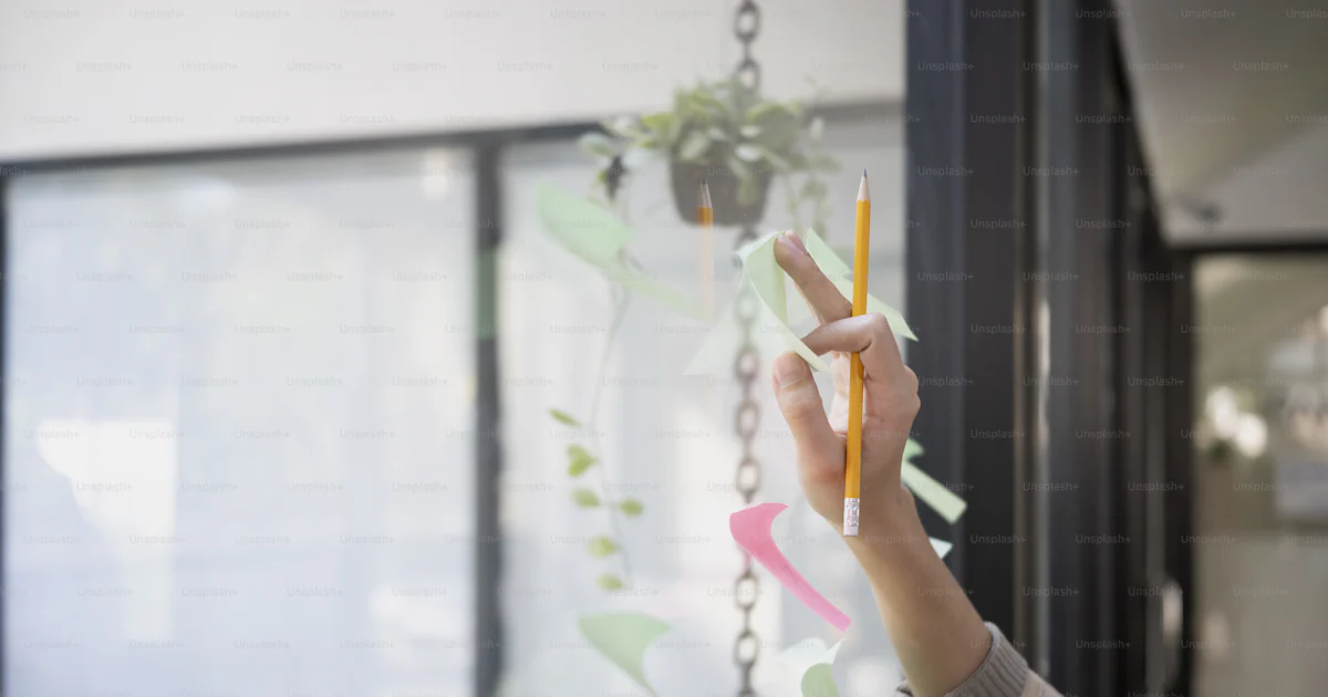 Cropped shot female designer putting colorful sticky note on a glass ...
