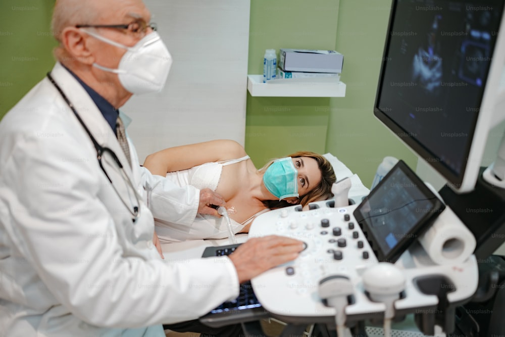 Ein erfahrener Oberarzt führt eine Herzuntersuchung an einer jungen Patientin durch. Er benutzt einen Kardiologie-Scanner. Medizin und modernes Technologiekonzept.