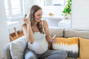 Primer plano de la mano de una mujer embarazada sosteniendo un dispositivo de prueba negativo. Feliz mujer embarazada mostrando su prueba rápida negativa de Coronavirus - Covid-19. Coronavirus