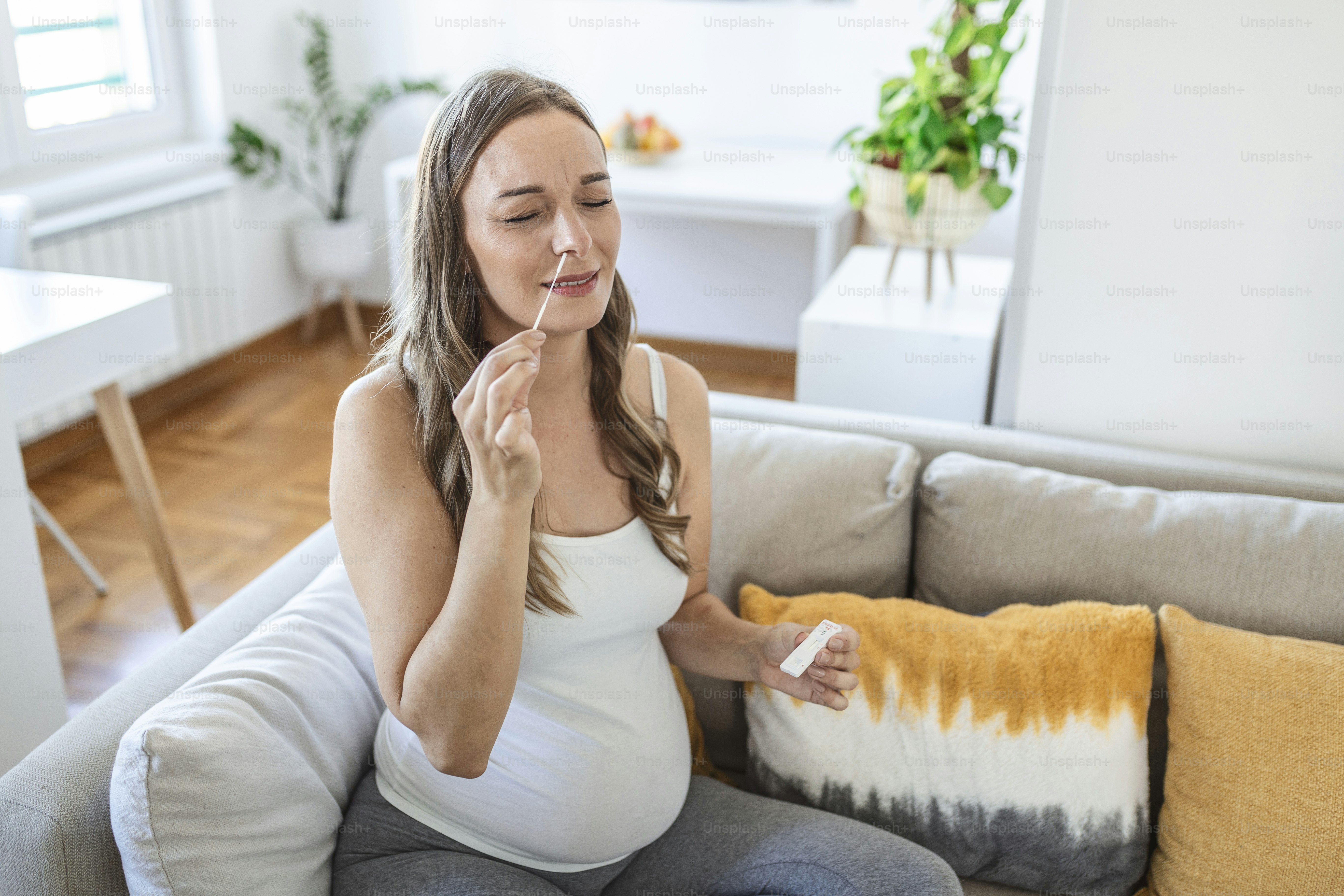 Pregnant woman taking a Self-swabbing home tests for COVID-19 at home with Antigen kit. Introducing nasal stick to check the infection of Coronavirus. Quarantine, pandemic.