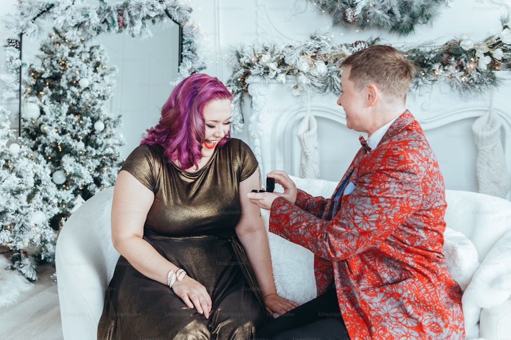 Homosexual gay butch proponiendo a su novia casarse con ella y dándole caja con anillo. Pareja de lesbianas LGBTQ celebrando las vacaciones de invierno de Navidad o Año Nuevo. Emoción positiva real y auténtica